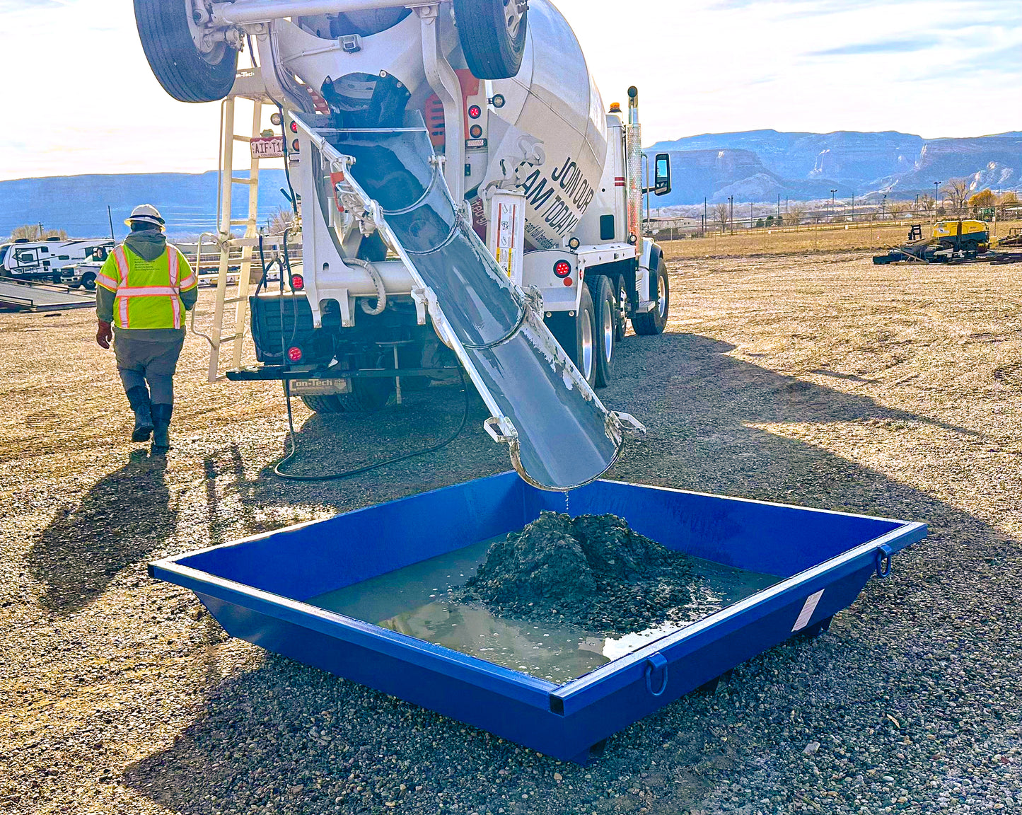 A concrete truck washing out into a concrete washout tub.