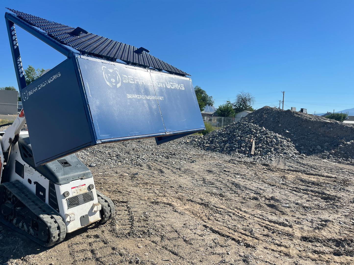 a ride on skid steer lifting a small grizzly rock screen