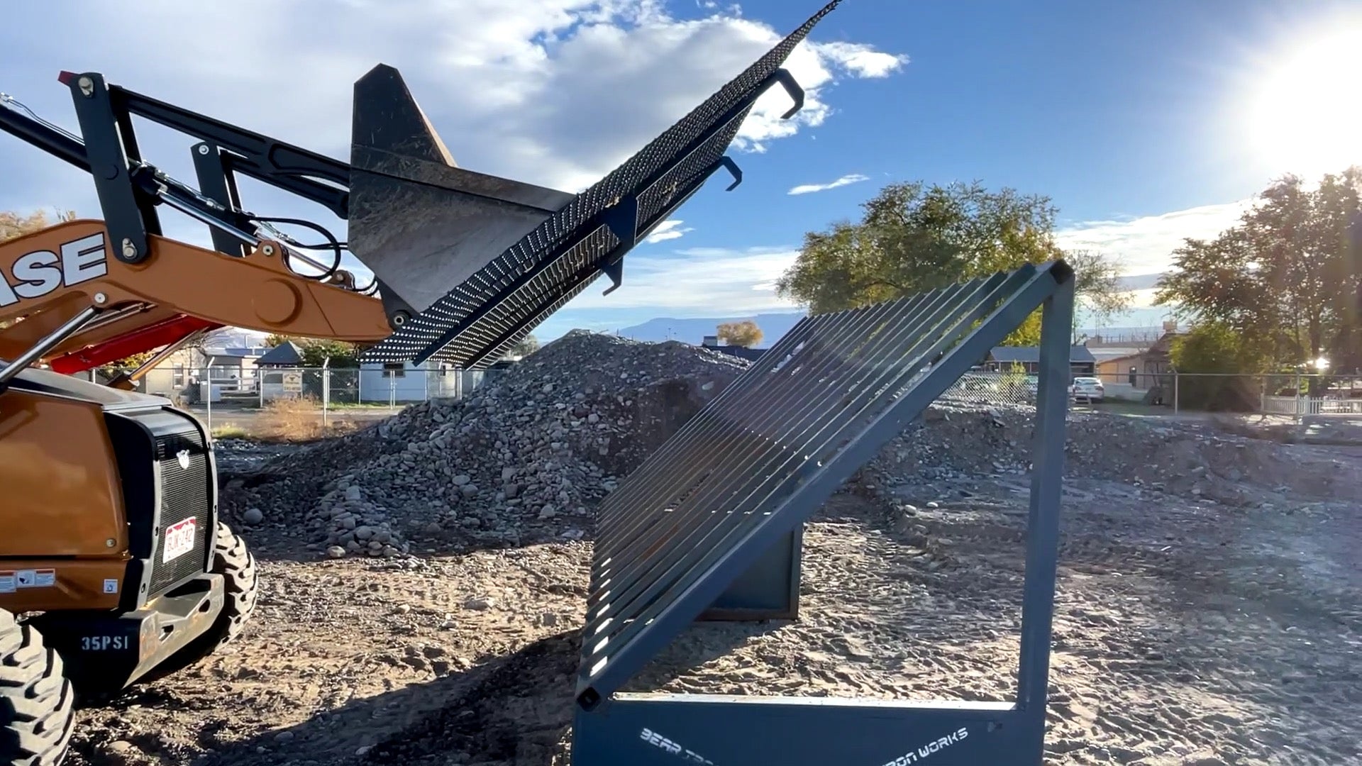 A backhoe changing the screen size on a grizzly rock screen.